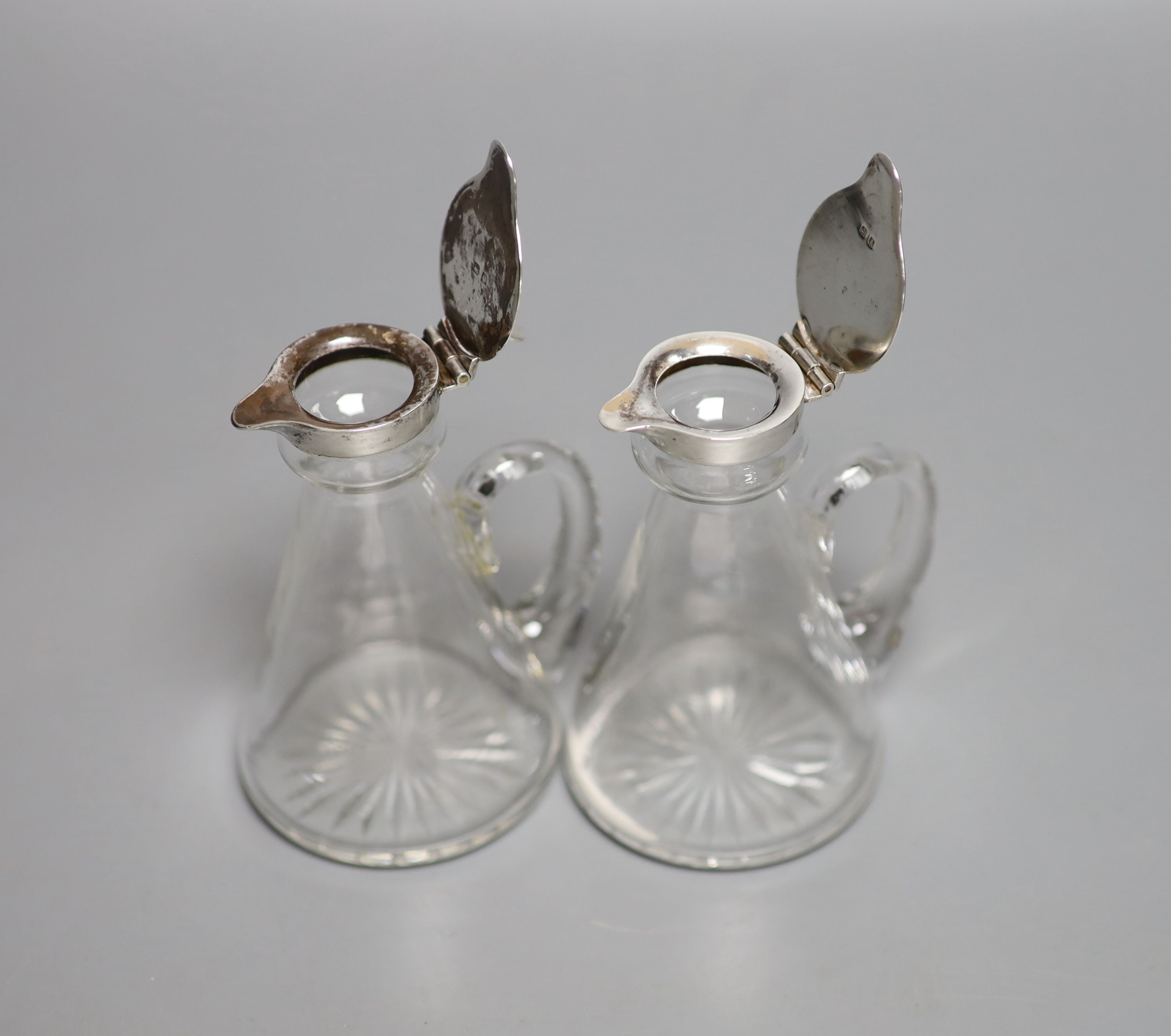 A pair of George V silver mounted glass whisky tot jugs, Hukin & Heath, Birmingham, 1925, 11.5cm.